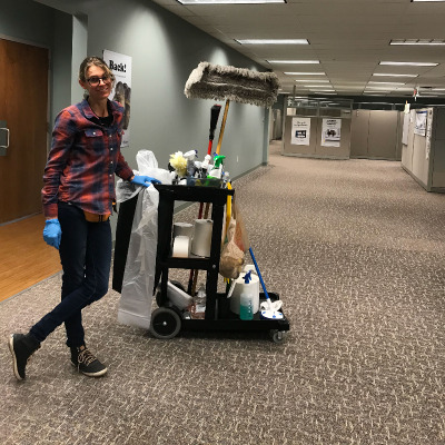 employee standing next to her janitorial cleaning cart